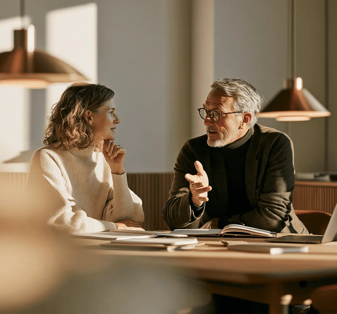 A client and a consultant in conversation at a long wooden table