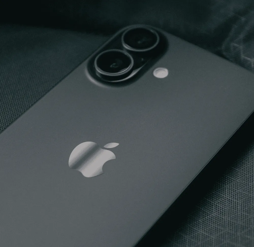 The back of a dark smartphone with its camera on a grey surface