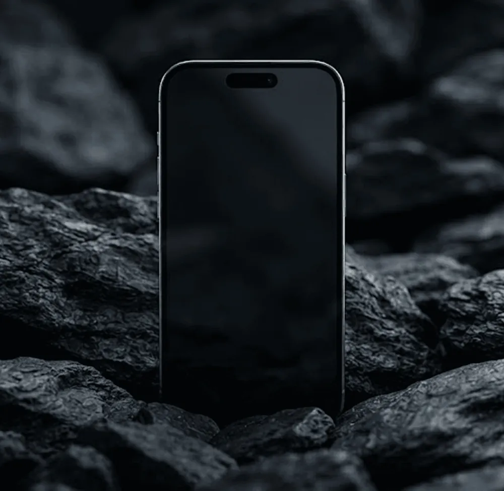Black smartphone standing upright among dark textured rocks