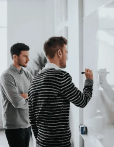 Two colleagues planning at a whiteboard