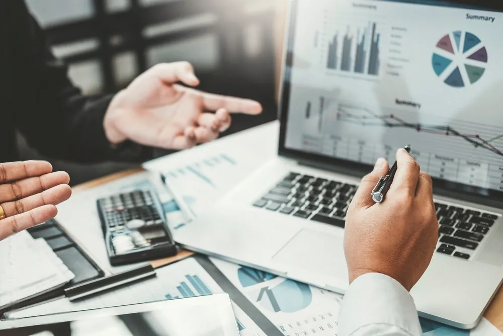 Hands pointing at charts on a laptop
