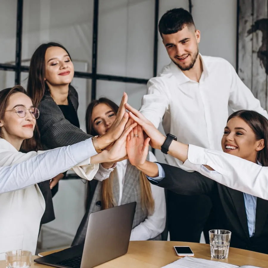 A team joining hands over a meeting table