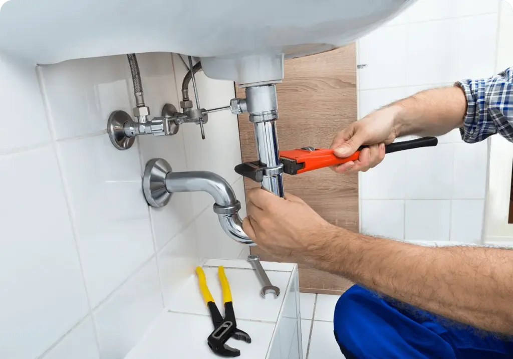 Gloved hands fitting a chrome tap, the tools laid out on the counter