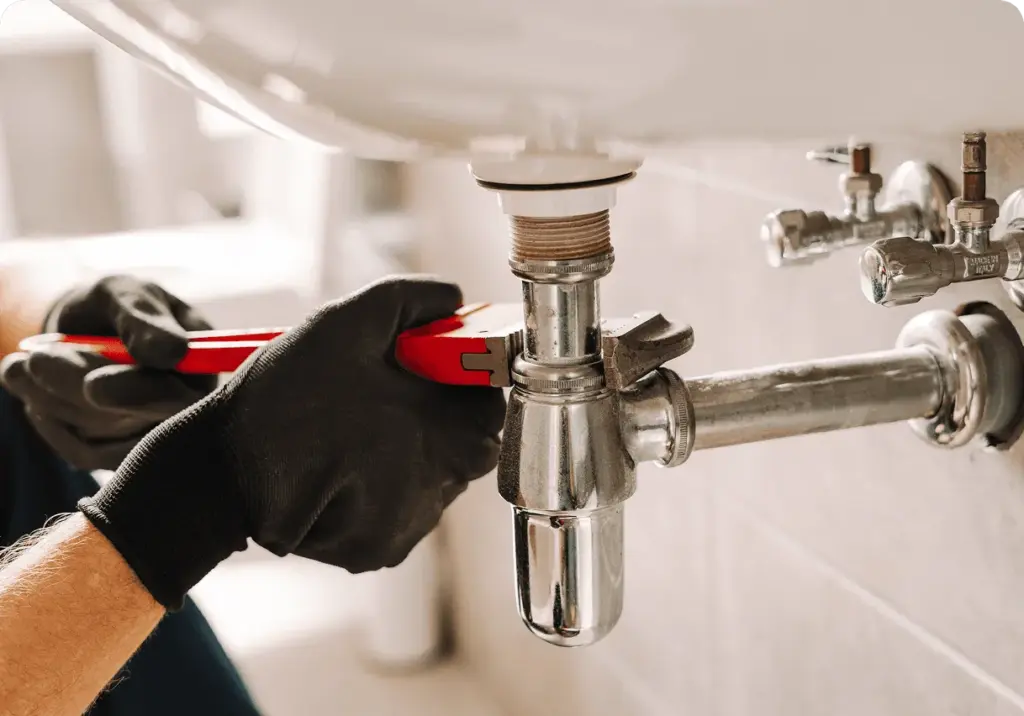 Gloved hands fitting a sink trap