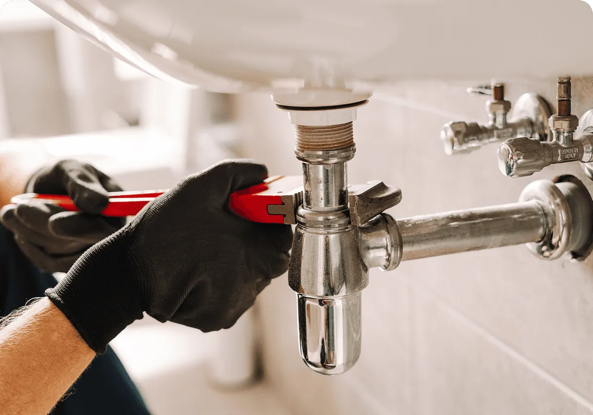 Gloved hands fitting a sink trap