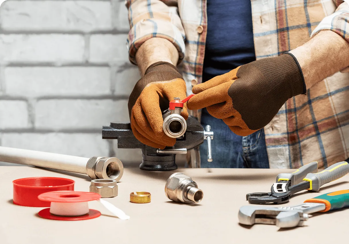 Hands tightening a pipe fitting with a wrench, the tools on the table