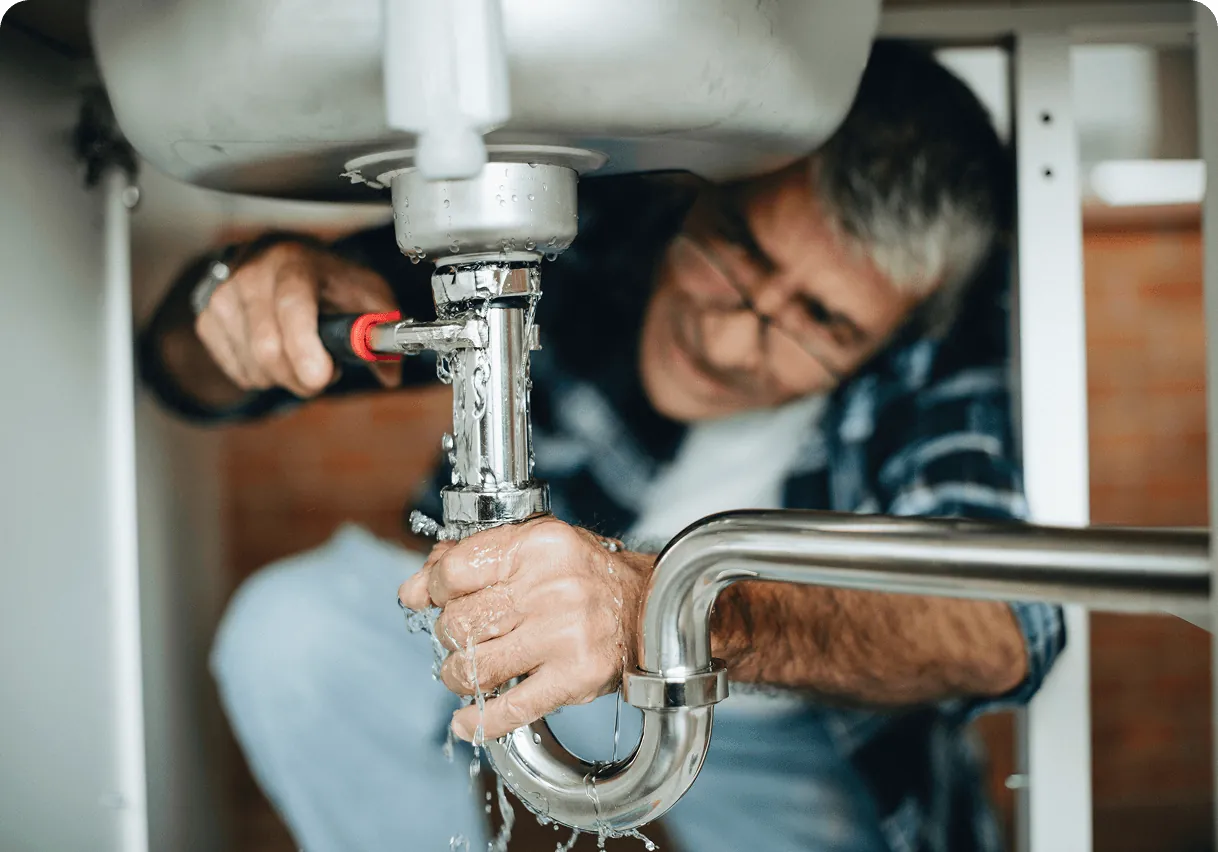 A plumber working on the pipes under a sink