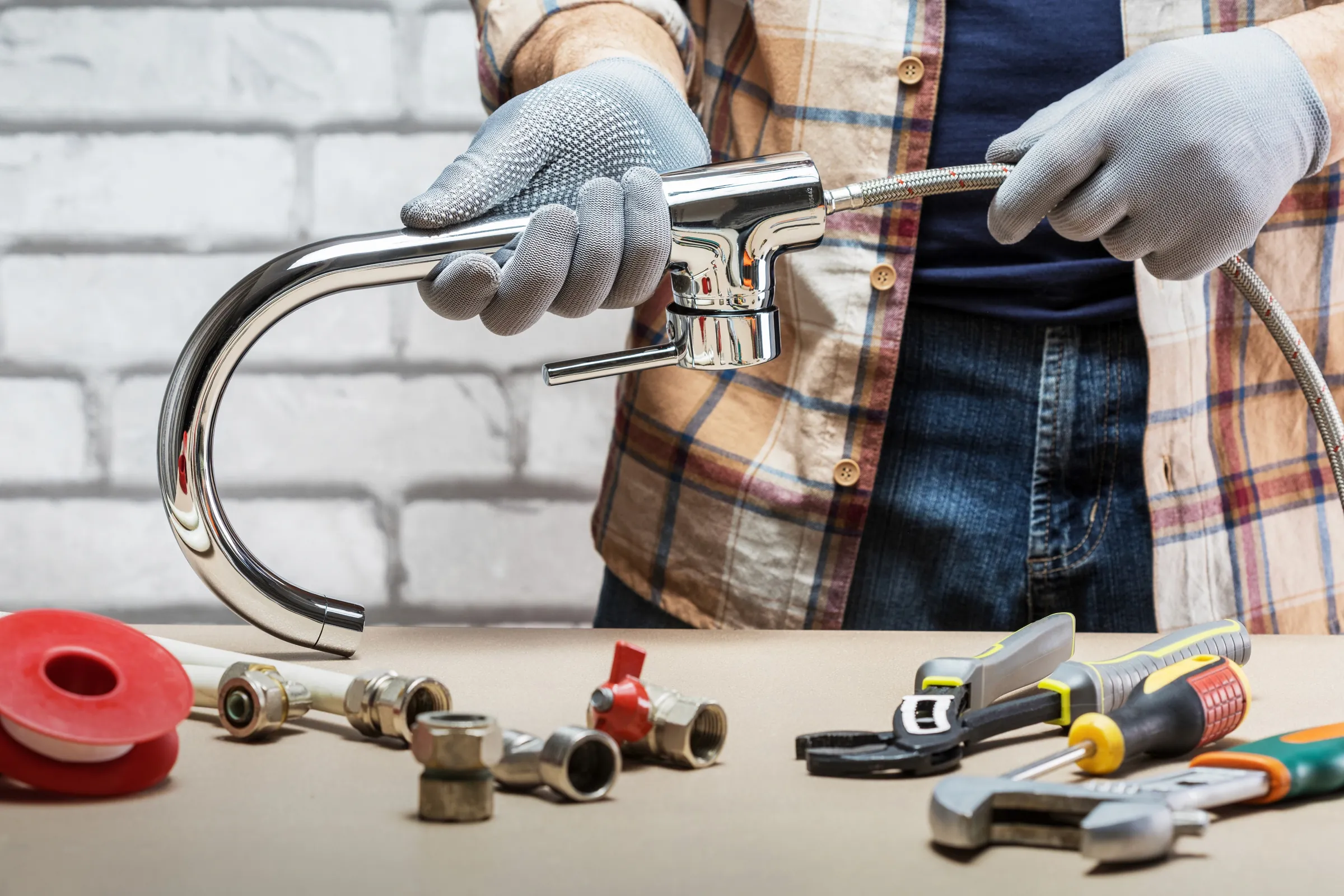 Gloved hands fitting a new kitchen tap, the tools laid out on the counter
