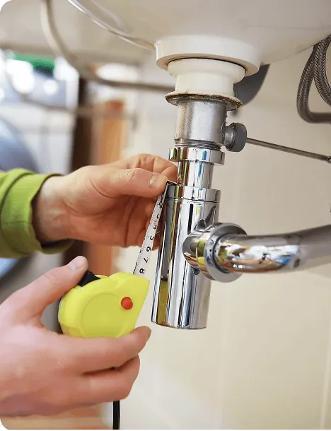 A hand fitting a chrome sink trap