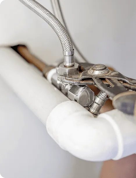 Pliers tightening a joint on a white water pipe