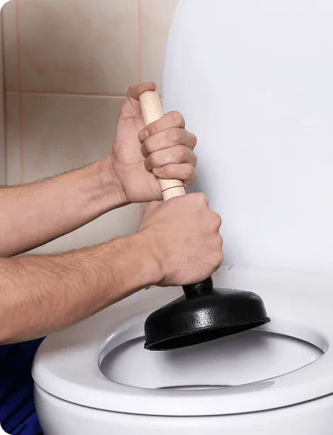Hands clearing a toilet with a plunger