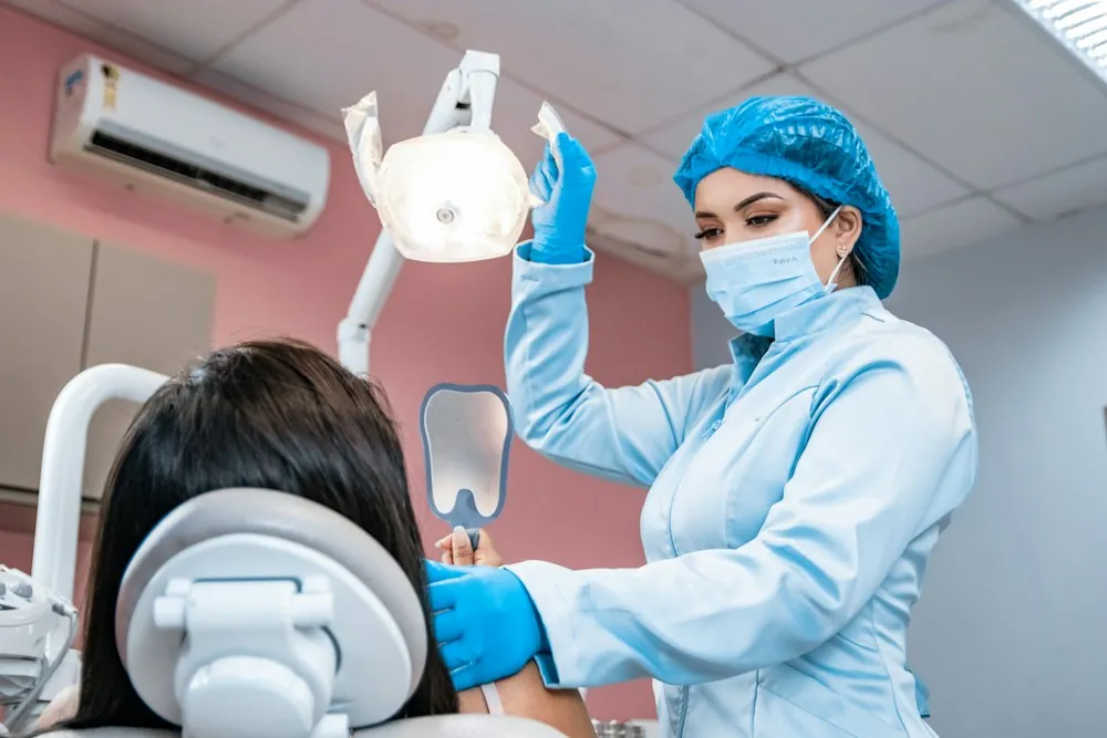 A dentist in a blue cap treating a patient