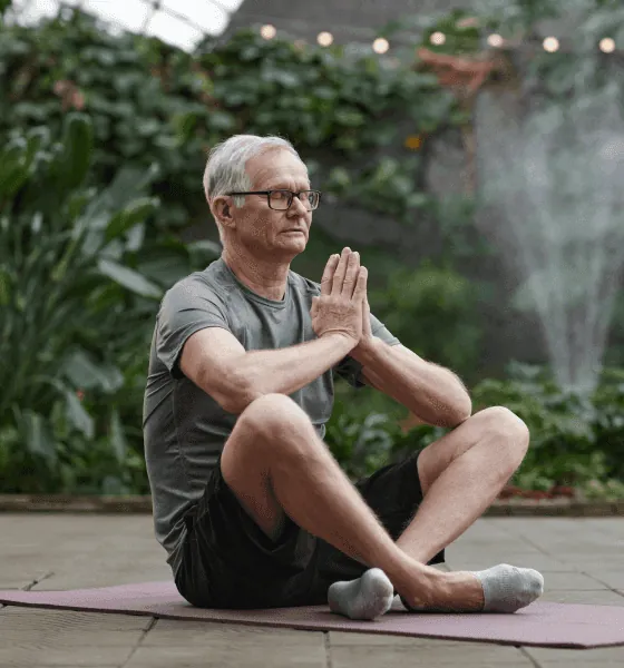 A man meditating on a mat outdoors