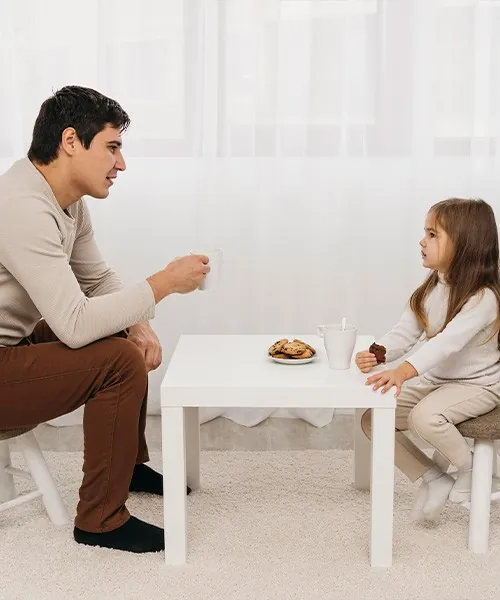 A father talking with his daughter at a small table