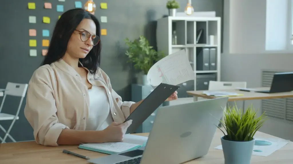 Woman reviewing papers at a desk with sticky notes