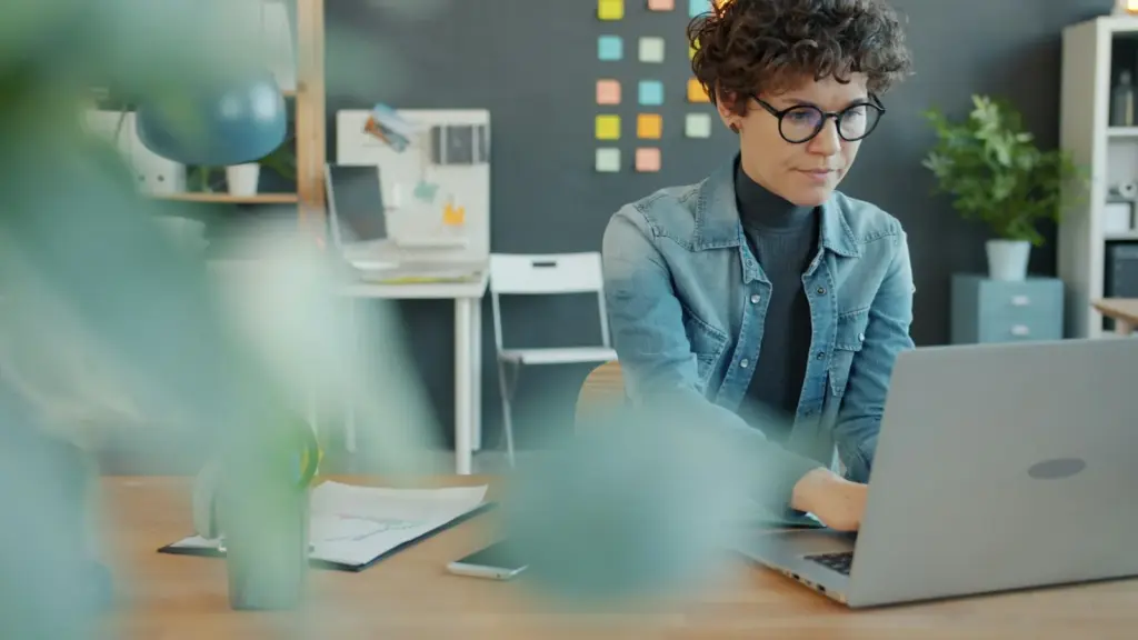 Woman with curly hair working at a laptop