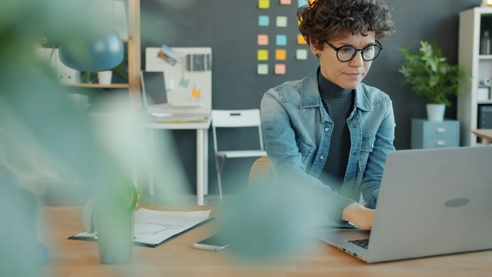 Woman with curly hair working at a laptop