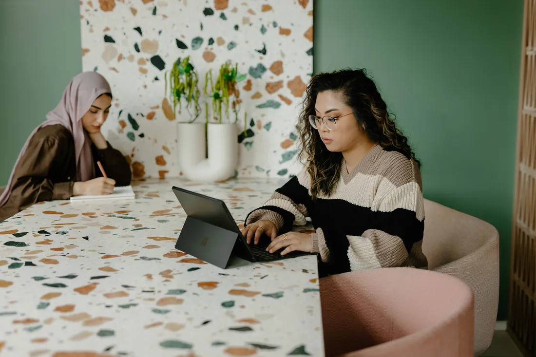Two colleagues working at a terrazzo table, one on a tablet
