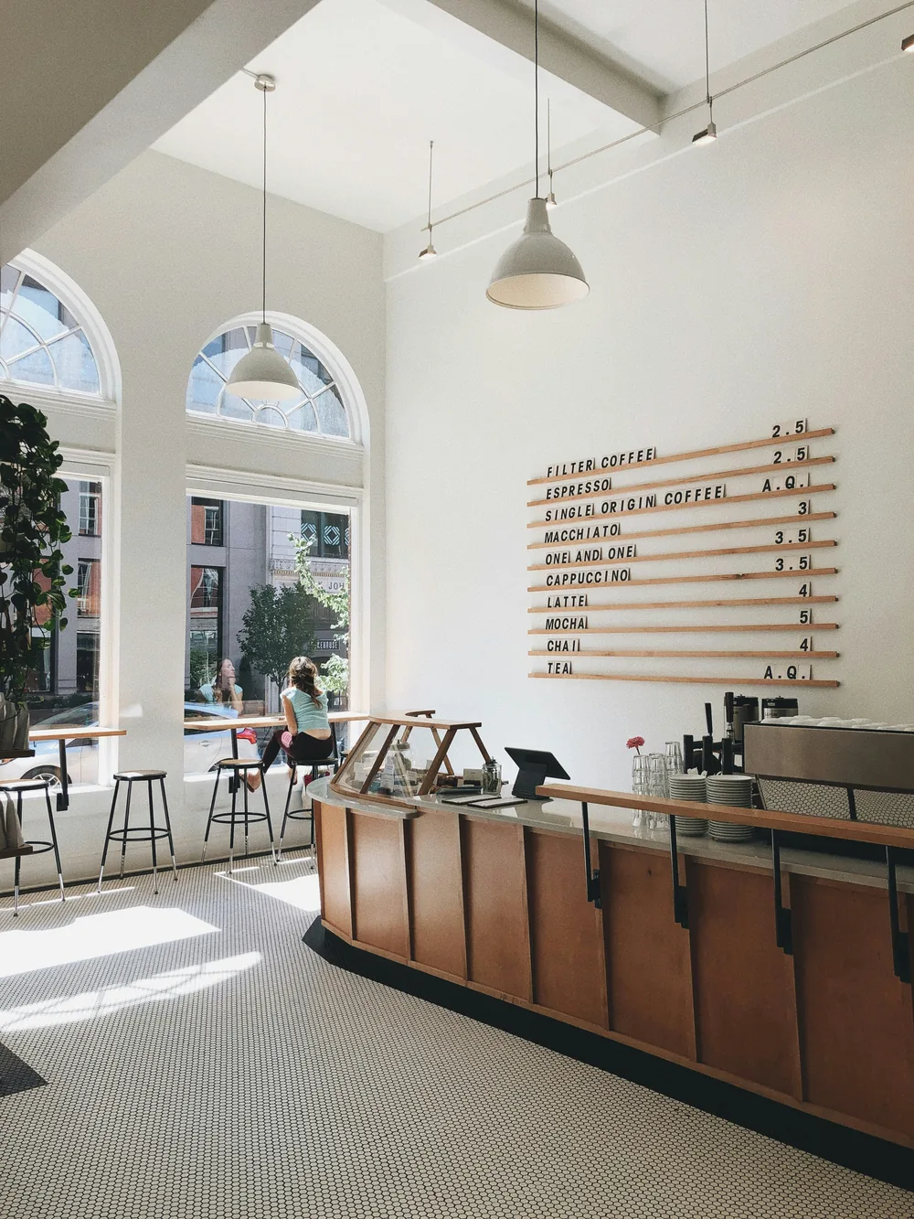 A bright café interior with arched windows and a long wooden counter