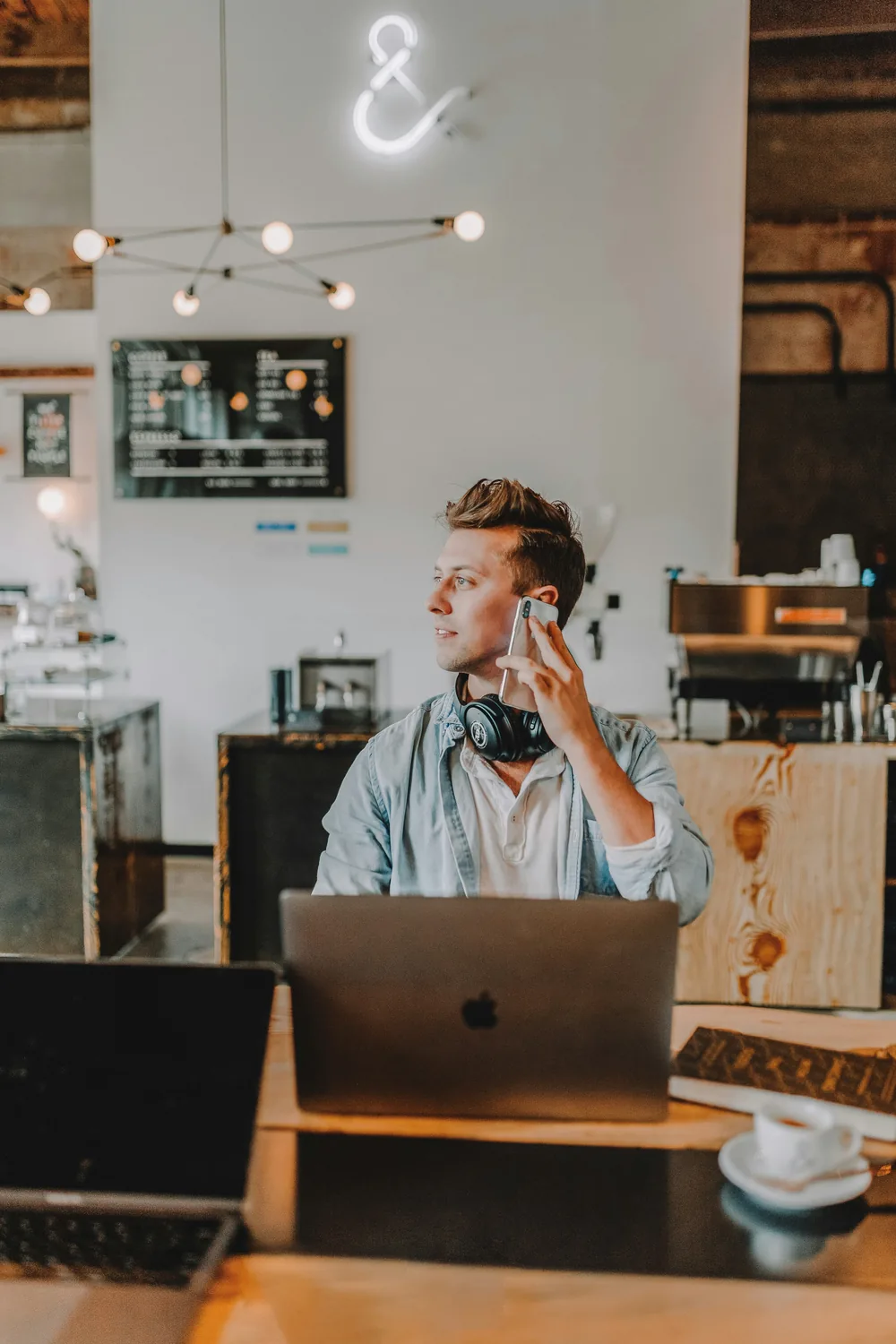 A regular on a phone call at a café table with his laptop