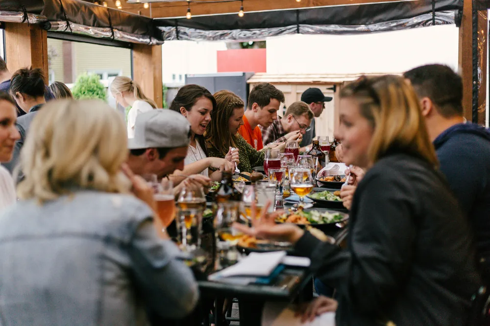 A long table of friends sharing a meal under string lights