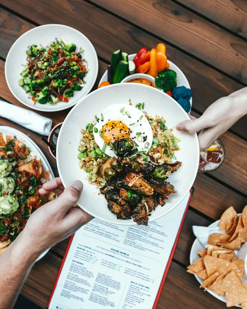 Friends sharing salads and grilled dishes over an open menu