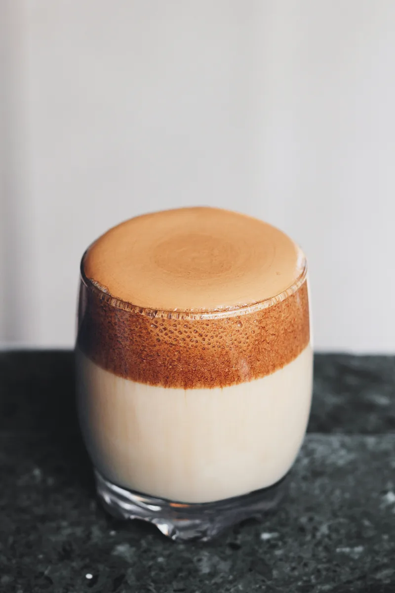 Whipped coffee layered over milk in a glass