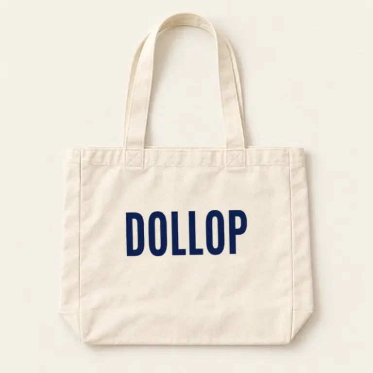 Cream canvas tote with a navy Dollop logo on a warm off-white background.