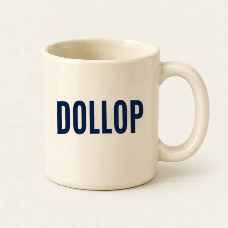 Ivory ceramic mug with a navy Dollop logo on a warm off-white background.
