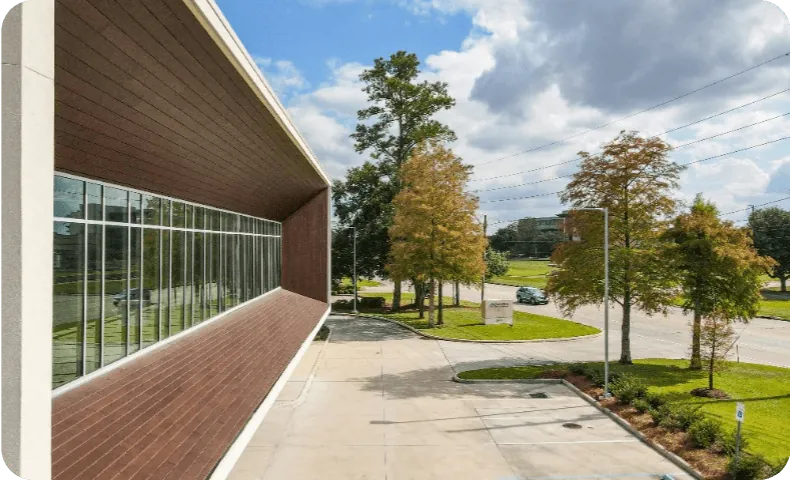 A modern building beside a tree-lined drive