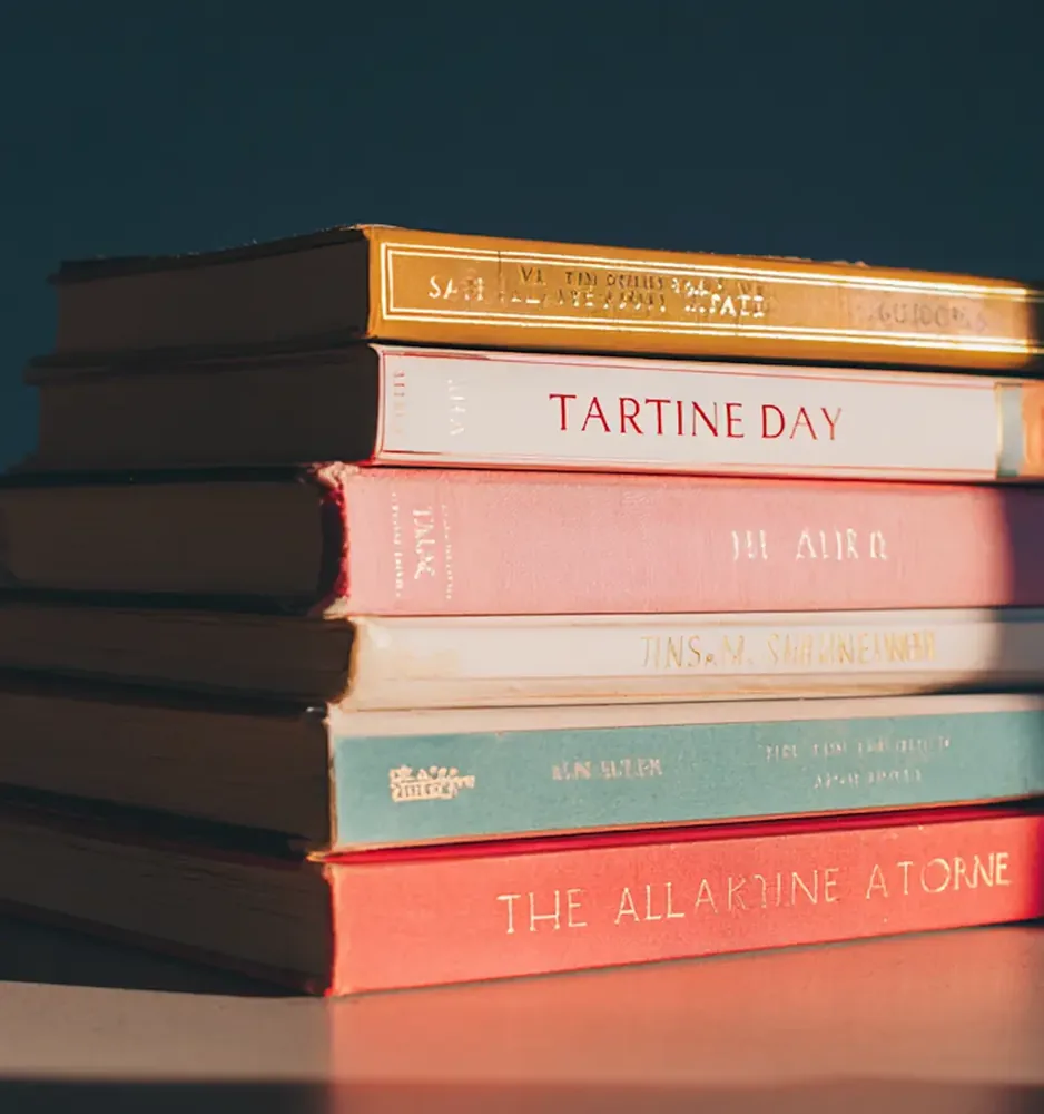 A stack of books with pastel spines in warm light