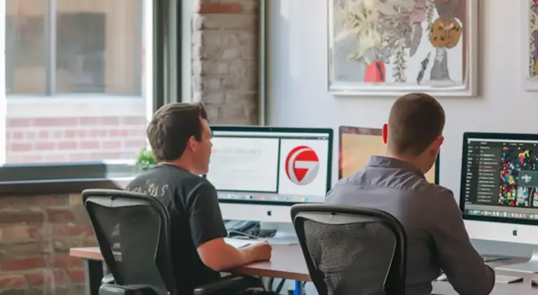 Two people at their desks in a bright studio office