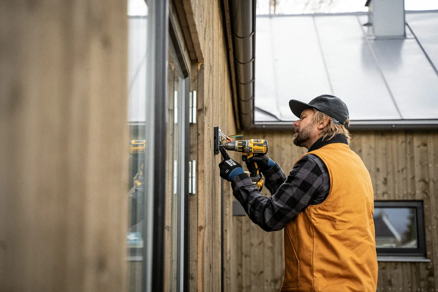 A tradesman drilling a window frame on a timber wall