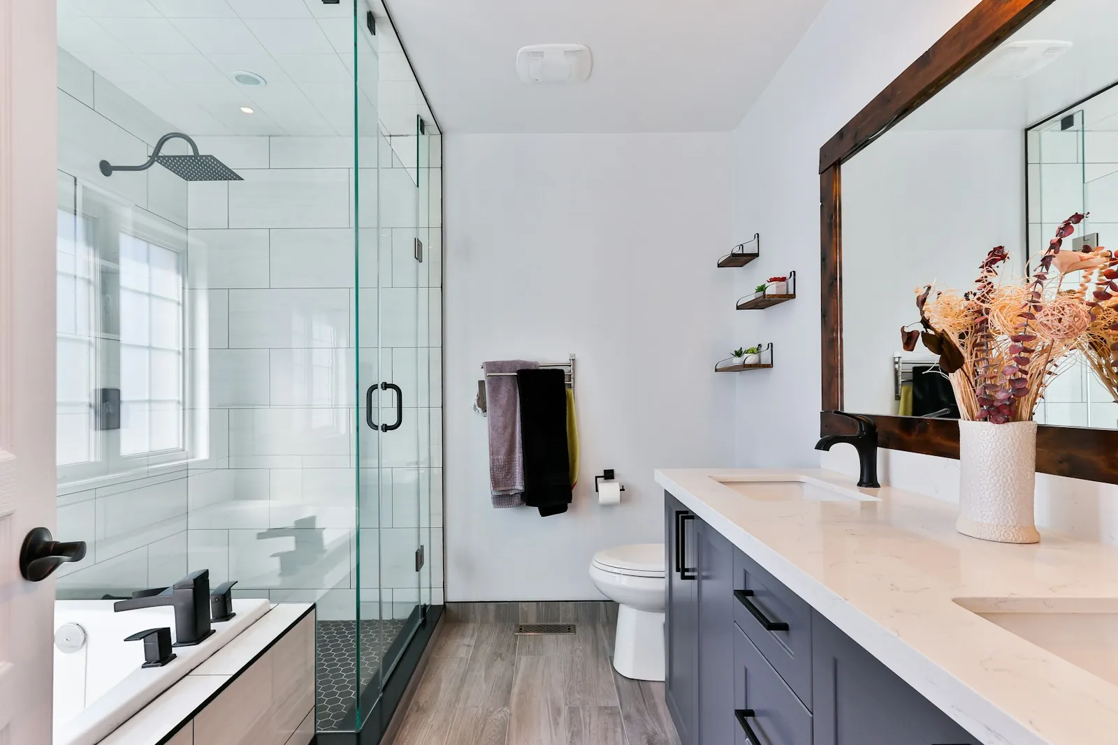 A bright bathroom with a glass shower and a timber mirror