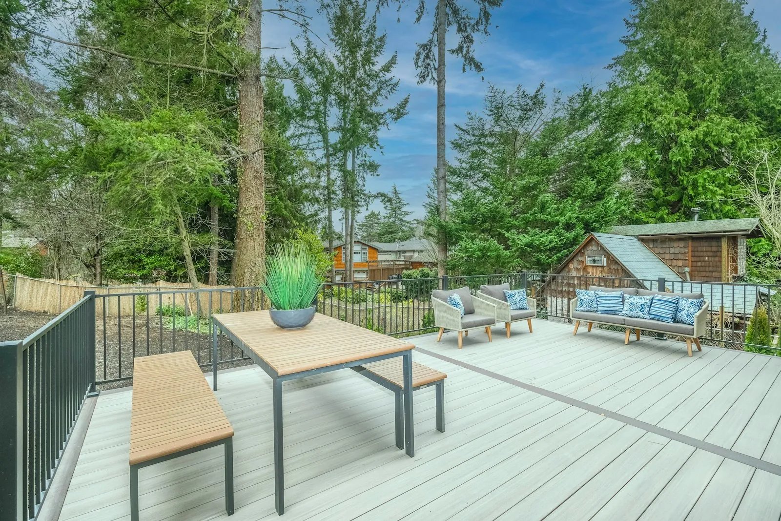 A deck with outdoor furniture among tall trees