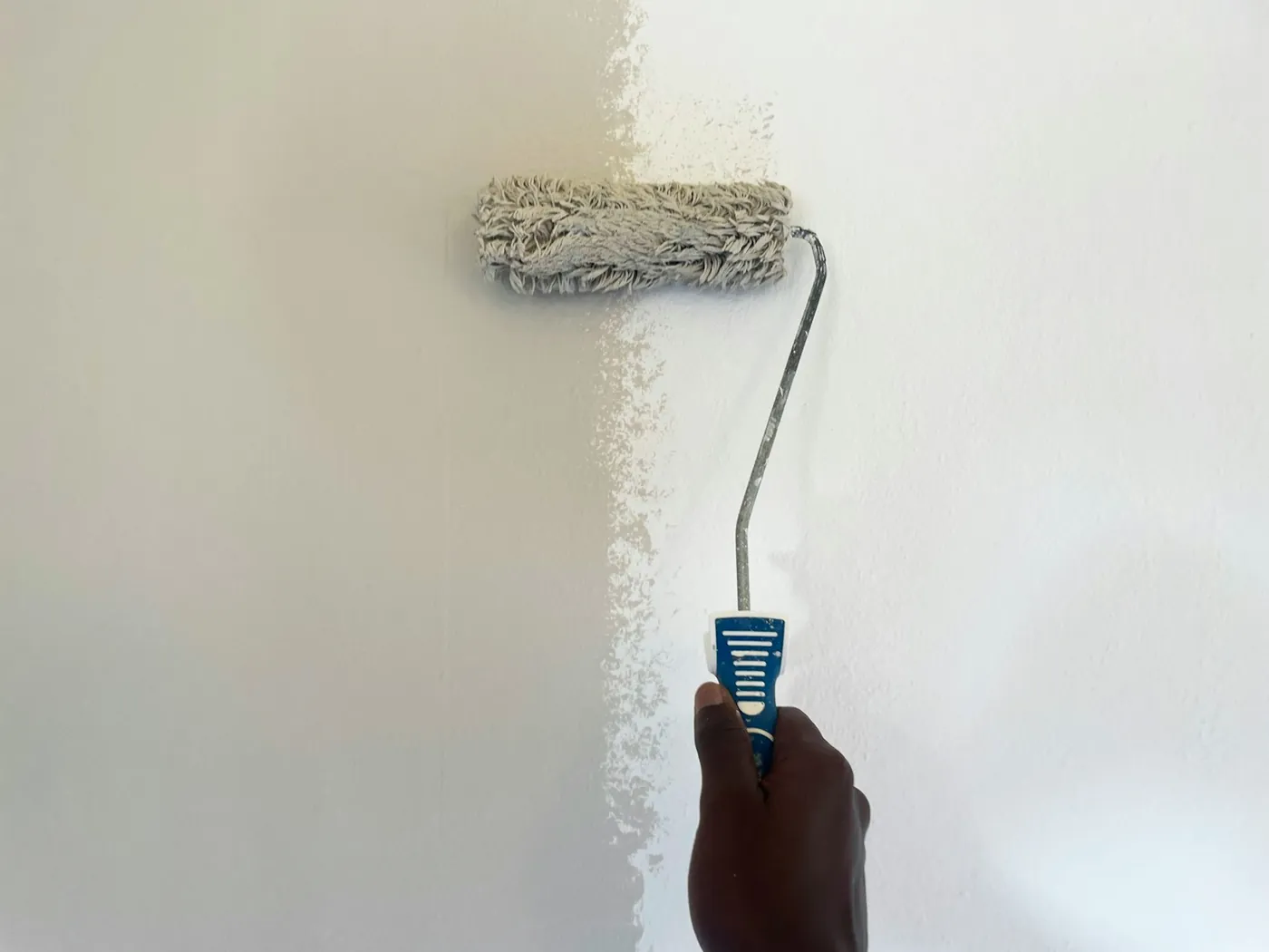 A paint roller on a freshly painted white wall
