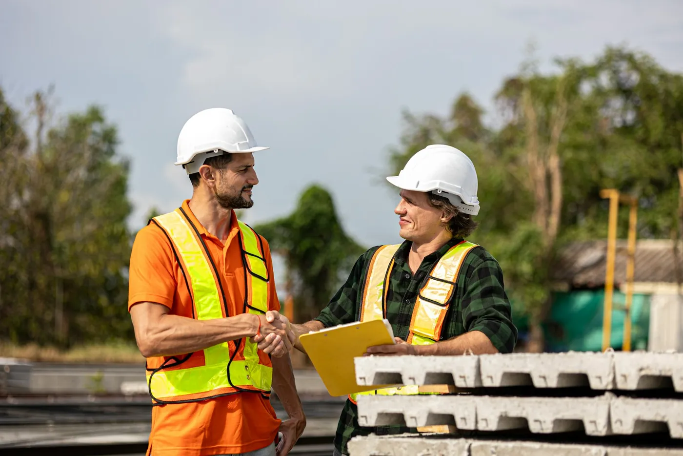 Two site workers shaking hands over a clipboard