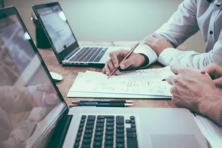 Two people going through documents next to a laptop
