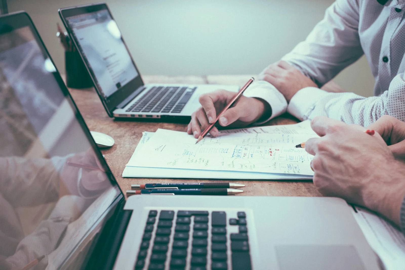 Two people going through documents next to a laptop