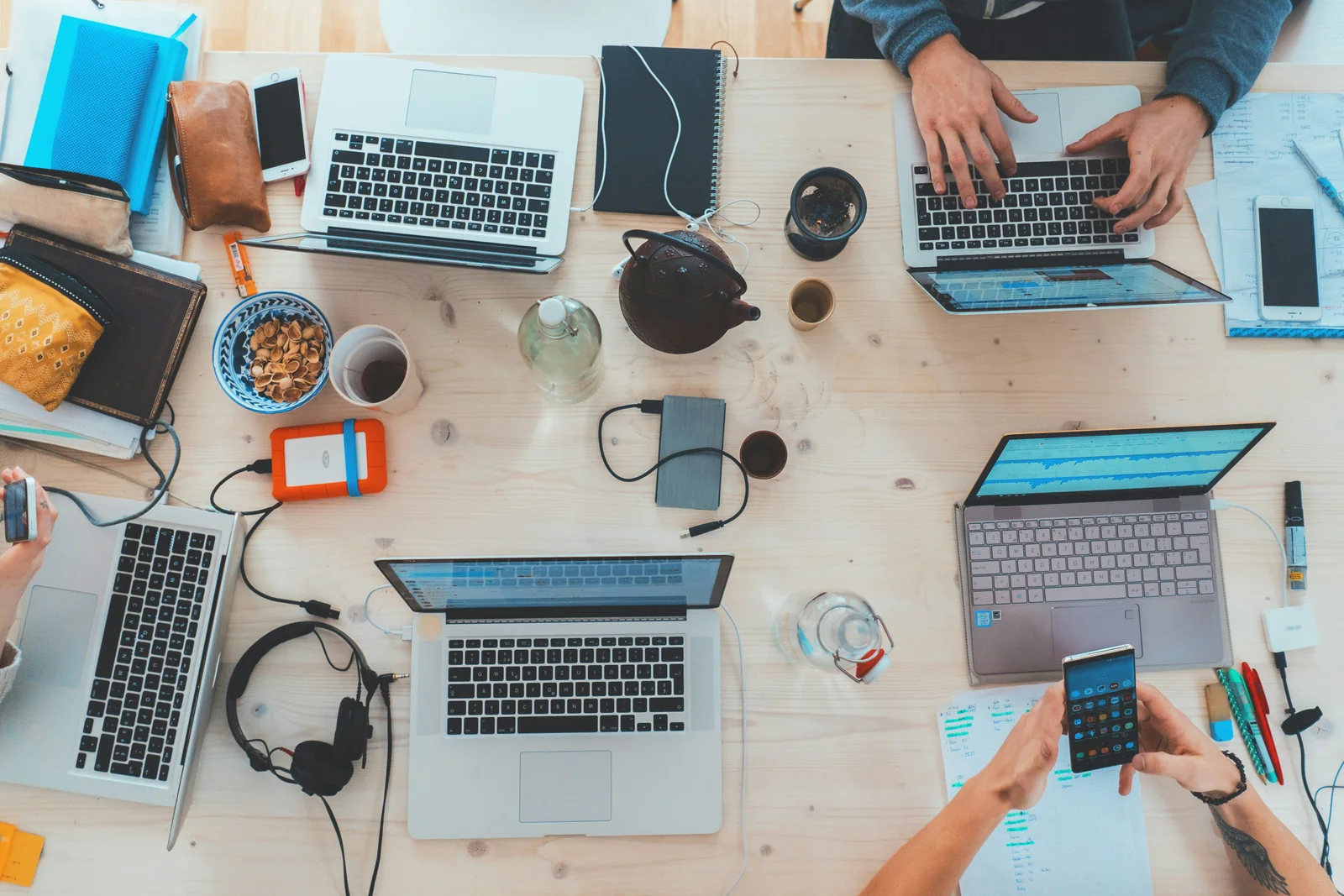 Laptops, phones and coffee on a shared table seen from above