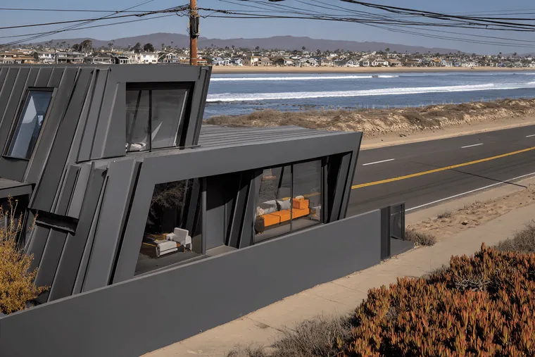 A dark angular house on the shore of a lake