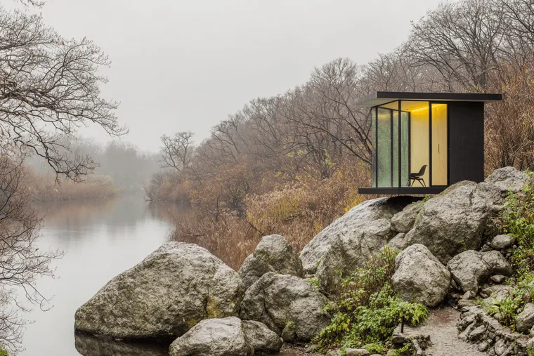A small cabin on the rocks above a misty lake