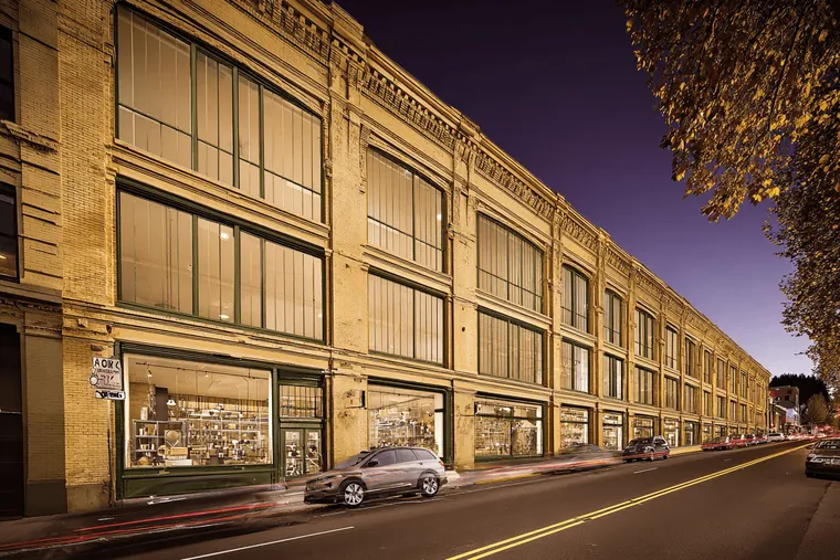 A tall warehouse building with lit windows at dusk