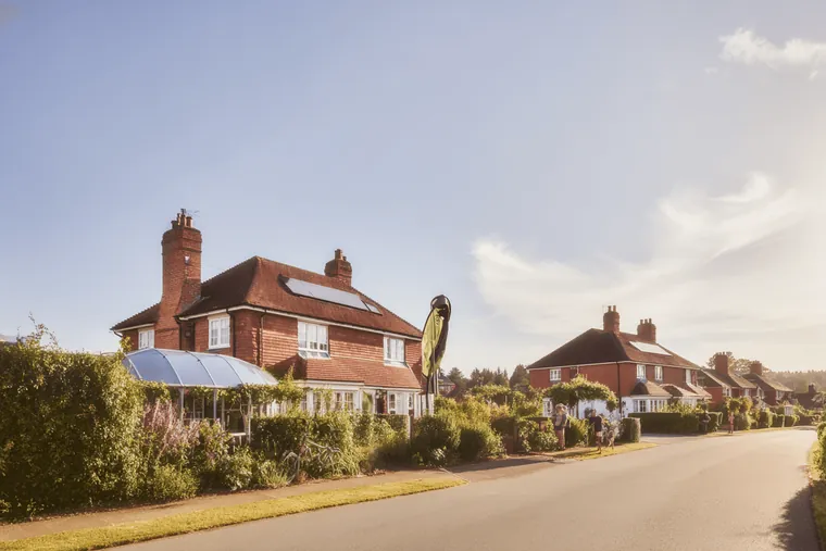 Brick houses along a road lined with hedges