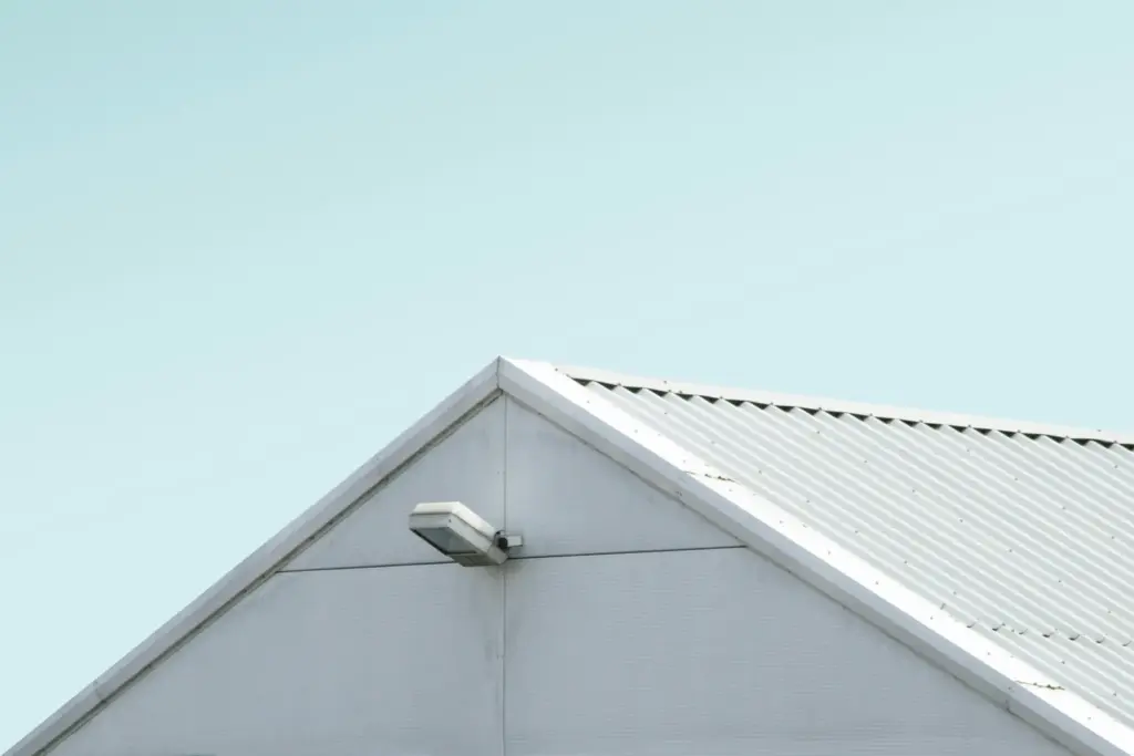 The gable of a metal roof against a clear blue sky