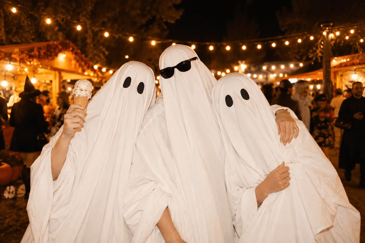 Guests wearing white sheet ghost costumes at a nighttime Halloween party