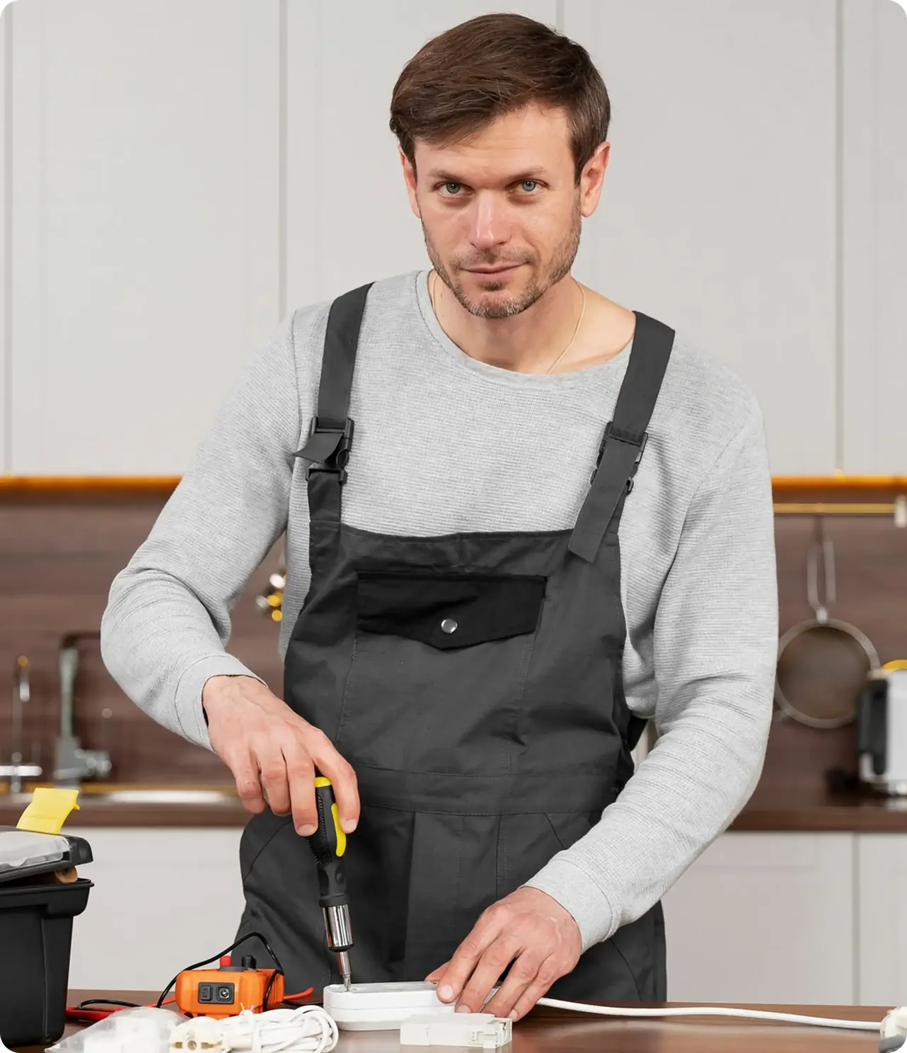 Gullwick technician in grey overalls working with a screwdriver in a kitchen