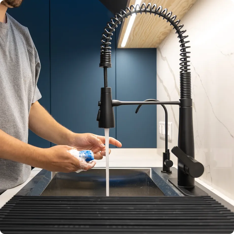 Hands rinsing under a modern black kitchen mixer tap