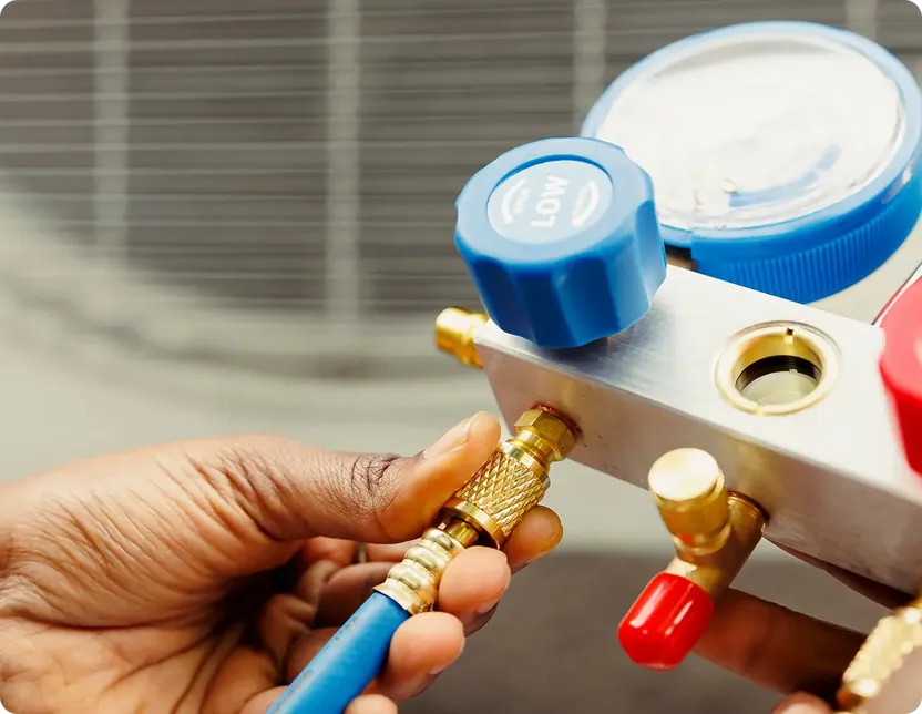 Technician connecting a blue hose to a refrigerant pressure gauge manifold