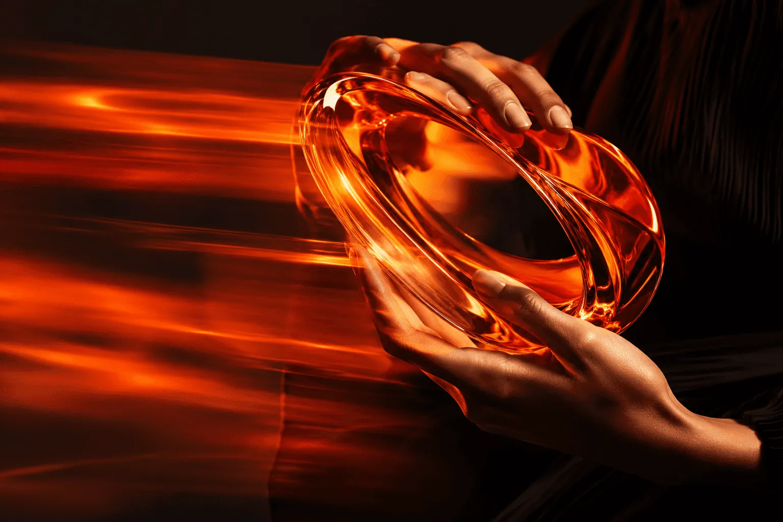 Hands holding a translucent orange glass object in dramatic light